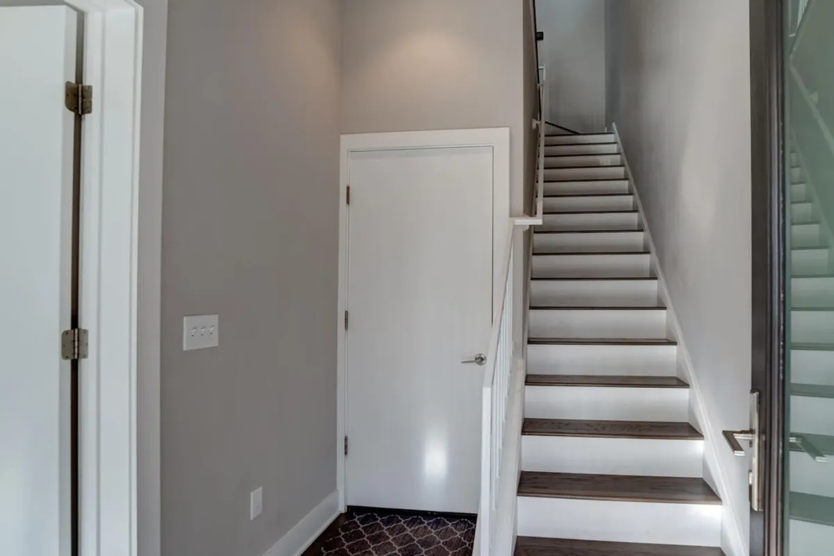 A bright and open interior scene showing a staircase and entryway, with a clear line of sight from the doorway. The area feels welcoming and spacious, setting the tone for the experience upon entering the home.